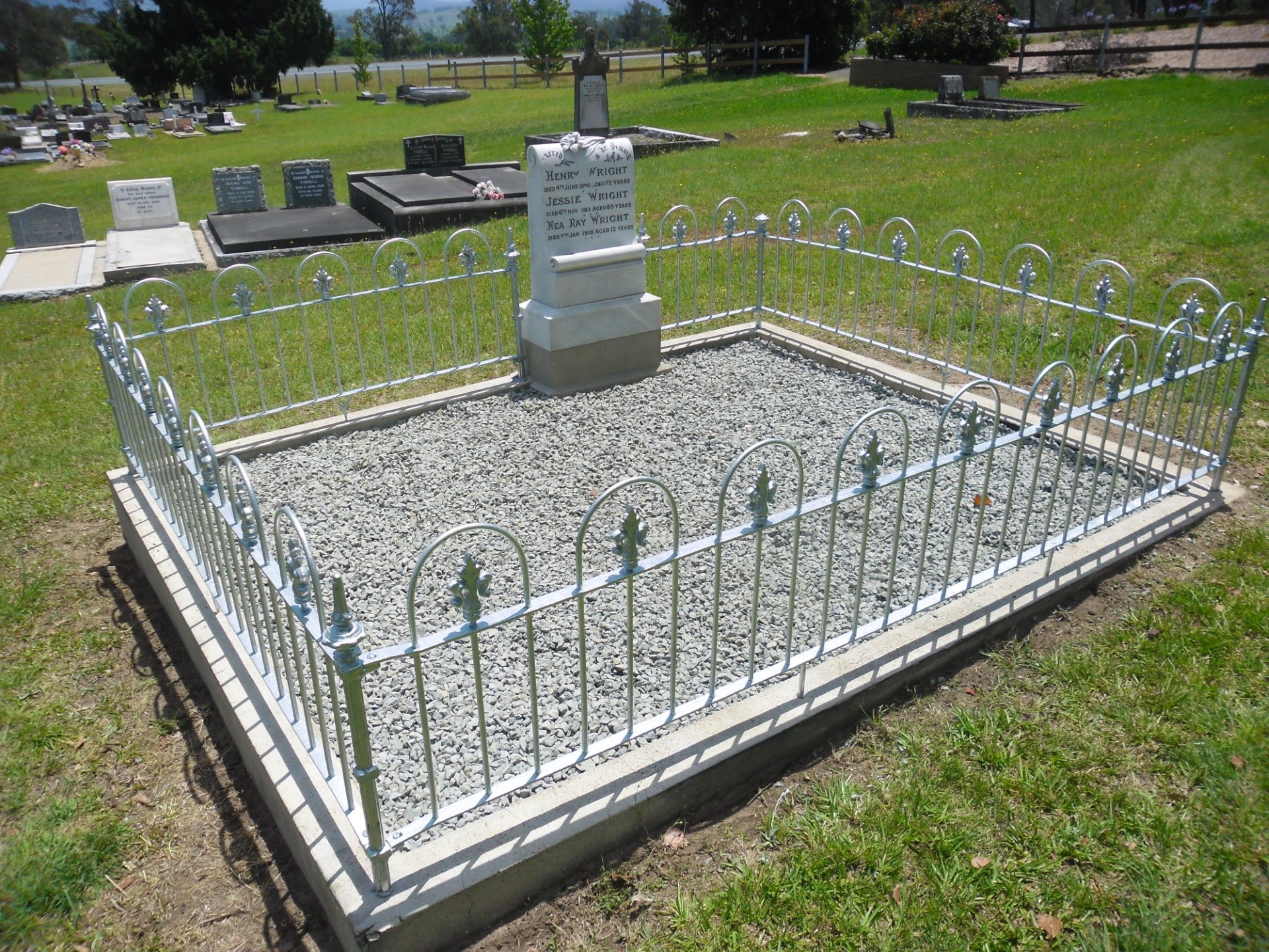 Wright family grave after restoration — white iron fence with fresh gravel and clean headstone