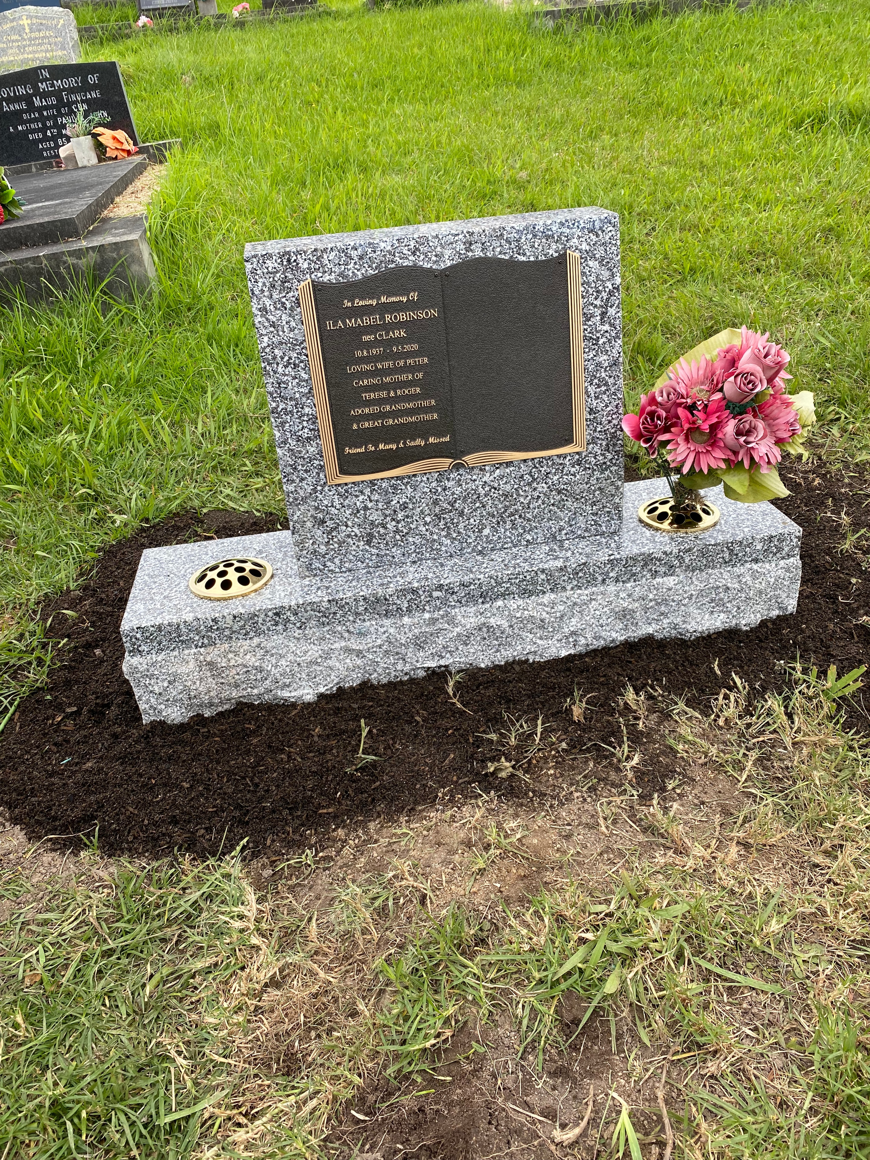 Ila Mabel Robinson bronze memorial plaque on granite monument with floral tribute