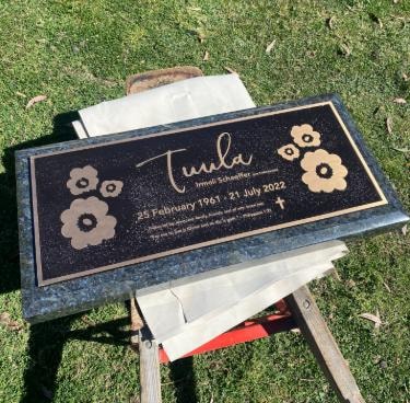 Linda Schaeffer black memorial plaque with floral motifs on blue granite